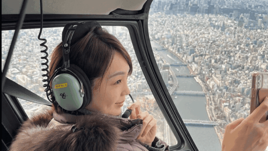 Helicopter soaring over Tokyo skyline with Mount Fuji in the distance.