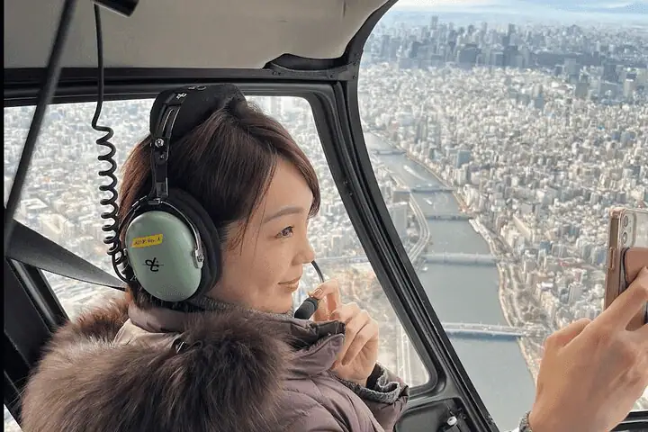 Helicopter soaring over Tokyo skyline with Mount Fuji in the distance.