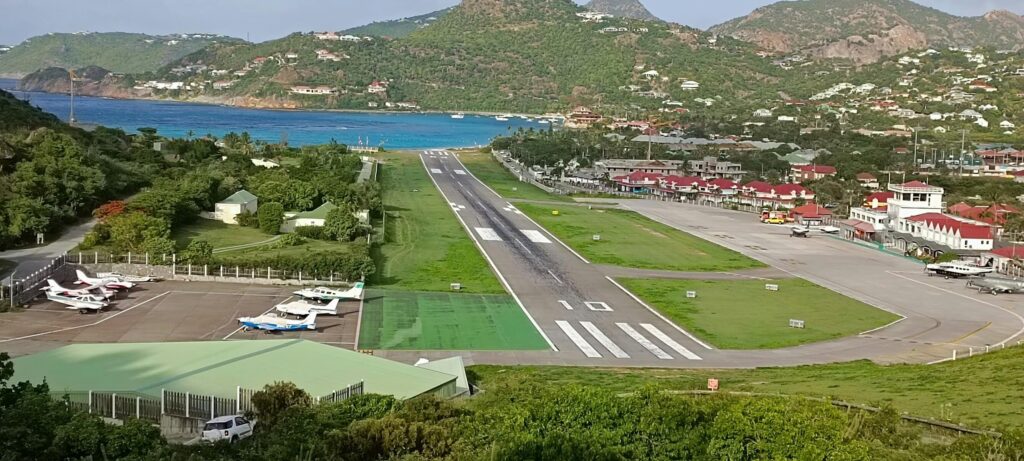 Private jet executing breathtaking airport landings at tropical island airport with ocean and hills surrounding runway