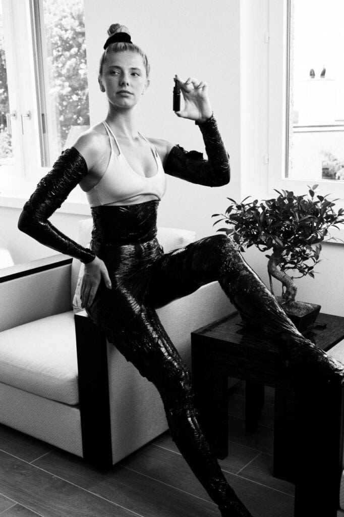 Professional model demonstrating SavaSano body wrap treatment application in modern spa setting, black and white artistic photography