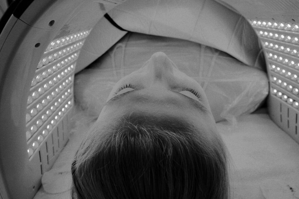 Client relaxing in infrared Cocoon therapy pod showing the precision-calibrated LED treatment interior, capturing the Swiss medical-grade technology